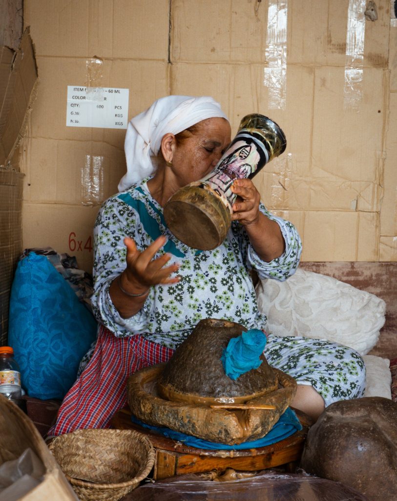 femme marocaine travaillant l'huile d'argan tout en s'amusant